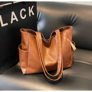 Detail of a brown leather tote bag with side pocket and soft pebble texture finish