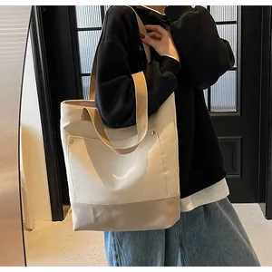 Canvas tote bag with color-block design and rivet pocket shown on shoulder by a model