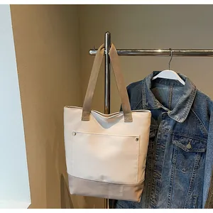 Detail of canvas tote bag with contrast stitching and exterior pocket on a display rack