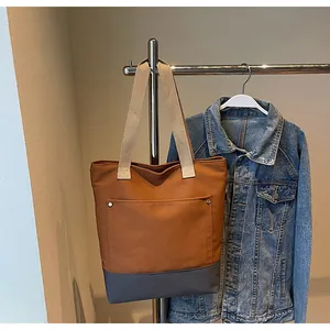 Detail of color-block canvas tote bag with side pocket and silver rivet accents