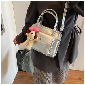 Detail of silver metallic bowling bag featuring a front pocket and plush dog charm