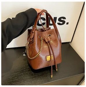 Dettaglio borsa a secchiello vintage marrone con catena dorata e ciondolo a sfera