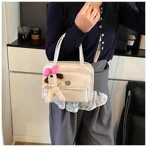 Close-up of cream bowling bag featuring a silver twist lock and cute dog plush charm