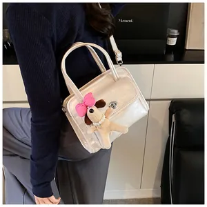 Detail of cream leather bowling bag with metallic clasp and cute puppy charm accessory