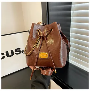 Dettaglio della borsa a secchiello marrone vintage con texture a pieghe e catena d'oro