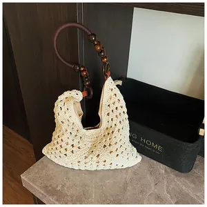 Detalle del bolso de ganchillo artesanal con asa de cuentas de madera y tejido crema