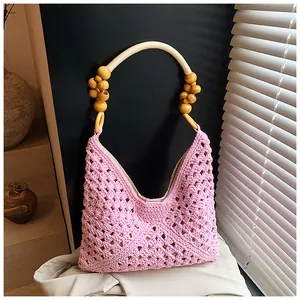 Detalle del bolso tote rosa de ganchillo a mano con asa de cuentas de madera y diseño calado