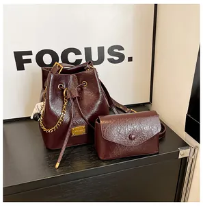 Dettaglio del set borsa a secchiello in pelle bordeaux cerata con eleganti finiture dorate