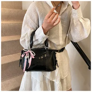 Close-up of black patent leather Boston bag with ribbon bow and heart pearl charm