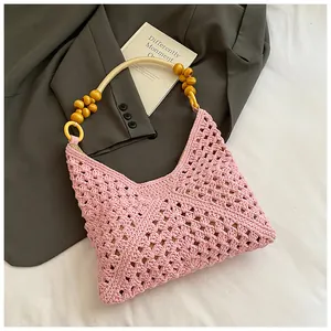 Detalle de bolso rosa de ganchillo con diseño de malla y asas de cuentas de madera