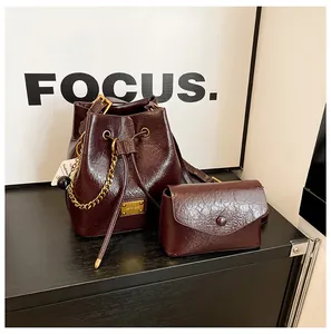 Dettaglio della borsa a secchiello plissettata bordeaux con catena d'oro e astuccio