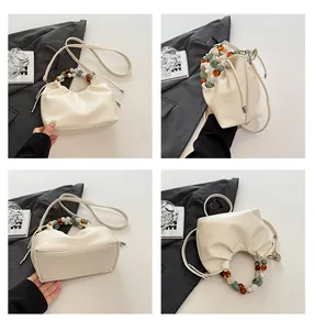 Vue détaillée du sac nuage crème avec texture litchi et poignée en perles colorées