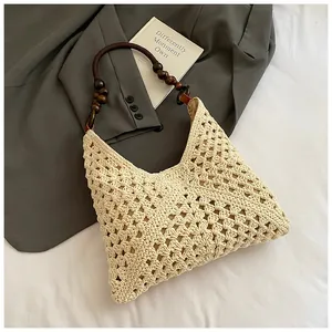 Detalle del bolso beige tejido a mano con correa de cuentas de madera oscura