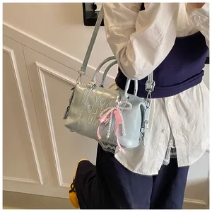 Close-up of light blue leather boston bag with embossed letters and pearl bow charm