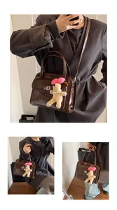 Detail of dark brown leather bowling bag featuring a plush puppy charm and silver twist lock