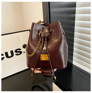 Dettaglio borsa a secchiello bordeaux in pelle lucida increspata con finiture dorate