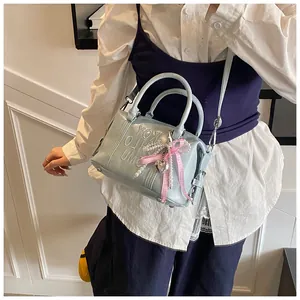 Close-up of a baby blue Boston bag featuring embossed letters and a pink ribbon charm