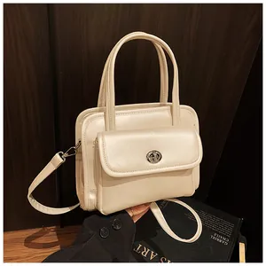 Detail of a cream leather bowling bag featuring a front flap pocket with silver turn-lock