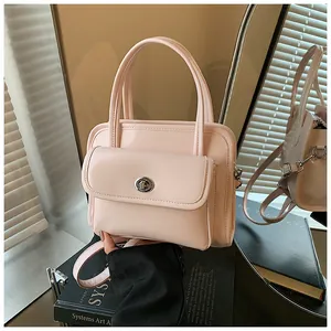 Detail of light pink glossy handbag featuring silver twist lock and dual top handles