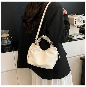 Détail du sac nuage plissé blanc avec poignée en perles colorées et bandoulière cuir