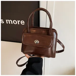 Close-up of glossy brown bowling handbag featuring silver metal twist lock and dual handles