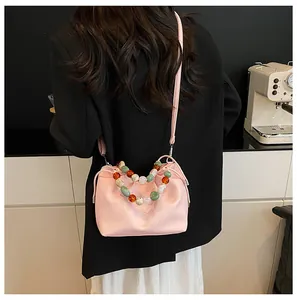 Sac nuage rose avec poignée en perles acryliques colorées sur une veste noire
