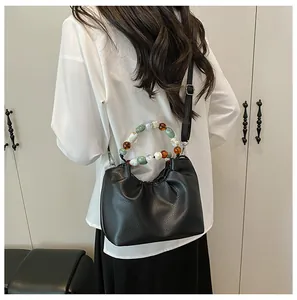 Détail du sac nuage plissé avec poignée en perles et bandoulière réglable