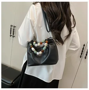 Détail du sac seau noir en cuir grainé avec poignée en perles et fermeture à cordon