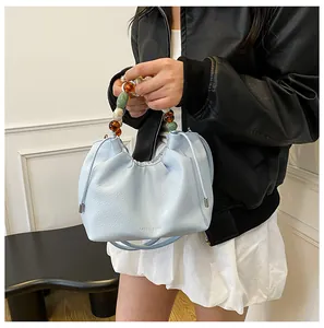 Détail du sac nuage plissé bleu clair avec poignée en perles et logo gravé