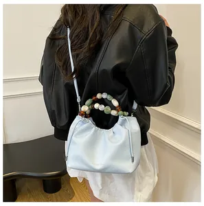 Détail du sac nuage plissé bleu clair avec une poignée en perles de marbre colorées