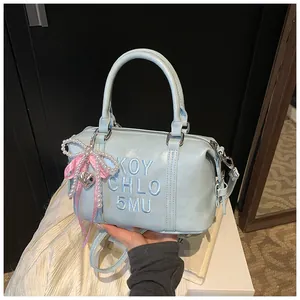 Detail of light blue Boston bag featuring embroidery, pearl bow, and leather texture