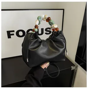 Détails du sac noir en cuir grainé avec poignée en perles colorées et cordon serrage