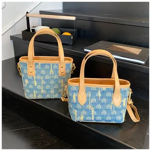 Dettaglio della borsa tote in denim effetto consumato con manici in pelle e metallo oro
