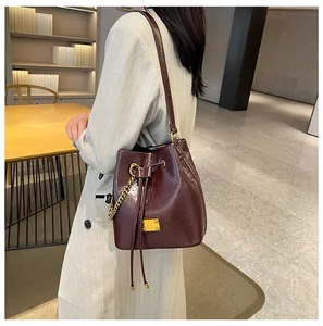 Dettaglio borsa a secchiello bordeaux in pelle lucida con coulisse e placca dorata