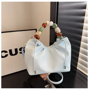 Détail du sac nuage bleu clair avec poignée perlée et logo Maidgee & Bag gravé