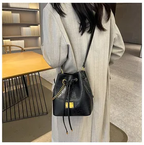 Dettaglio della borsa a secchiello nera minimalista in pelle con finiture in metallo oro