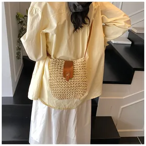 Detail shot of woven bucket bag featuring brown leather flap and golden metal button