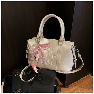 Close-up of beige Boston bag with pearl bead, pink checkered bow and heart charm