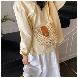 Detail of handwoven beige straw crossbody bag with brown leather flap and magnetic clasp