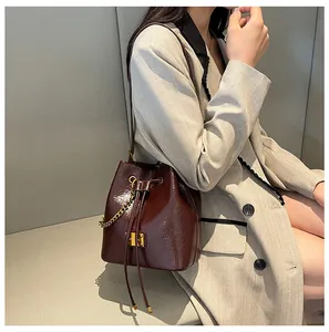 Dettaglio borsa a secchiello bordeaux lucida con coulisse e logo in metallo dorato