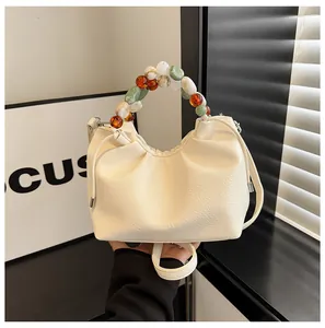 Détail du sac nuage blanc cassé avec poignée perlée et finition cuir grainé litchi