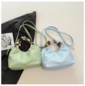 Détails de la poignée en perles et cuir texturé des sacs nuages vert et bleu