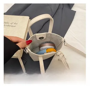 Dettaglio della mini borsa beige che mostra capacità interna e chiusura magnetica argento