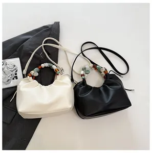 Détail de sacs nuages froncés en crème et noir avec des poignées en perles chic