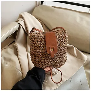 Detail of hand-woven straw bucket bag with vintage brown leather flap and magnetic buckle