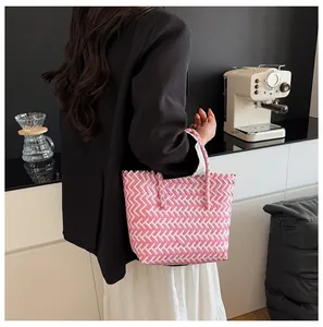 Sac cabas tressé rose et blanc porté à l'épaule pour illustrer la taille et le style décontracté