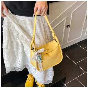 Detail of bright yellow leather handbag with metal twist lock and cute pendant