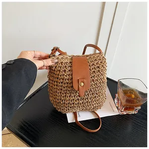 Close-up of hand-woven straw bucket bag with leather flap and metal buckle detail