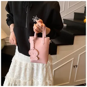 Mini borsa rosa in pelle martellata con ciondolo a cane su una scala elegante