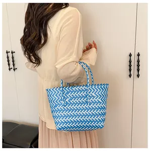 Détail du grand sac cabas tressé à carreaux bleu et blanc porté par un mannequin